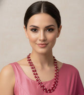 Woman wearing a red beaded necklace against a plain background
