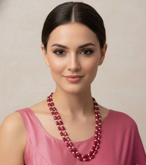 Woman wearing a red beaded necklace against a plain background